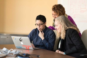 Minority business owners sitting at a laptop discussing Federal business programs