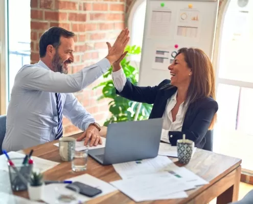 Man and woman giving each other a high five after completing their SAM renewal paperwork